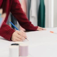 Professional beautiful Asian female fashion designer working with fabric sketches and drawing clothing design at the studio. Lifestyle women working concept.